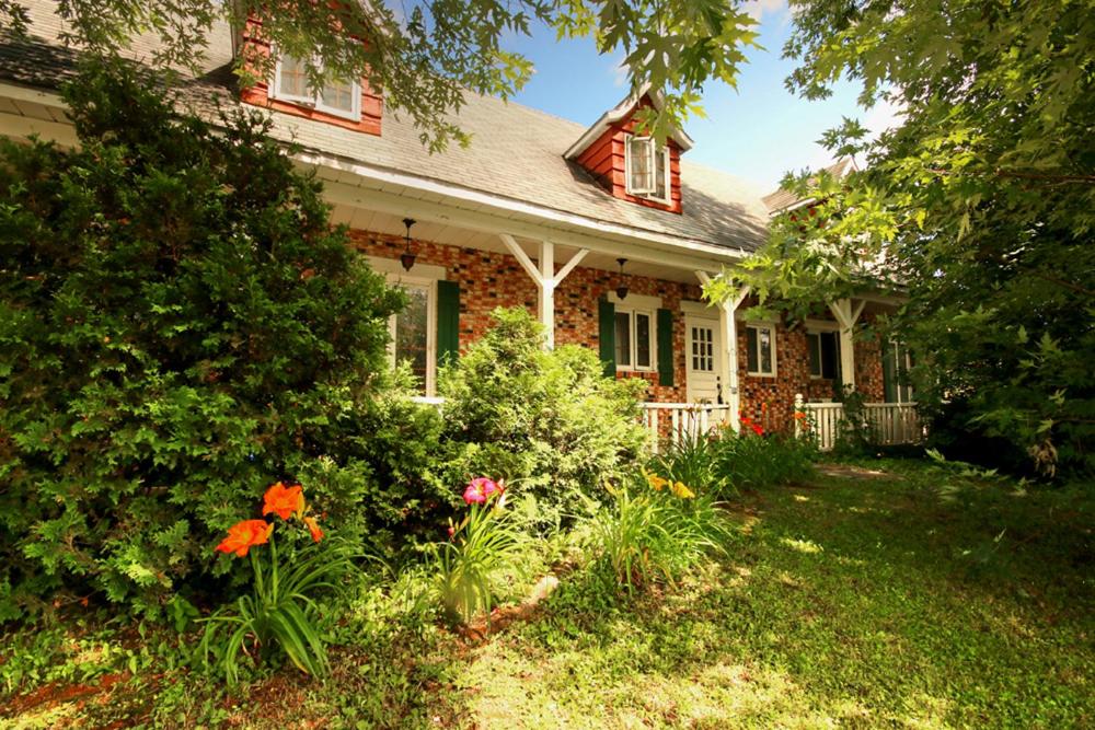 a brick house with flowers in front of it at Vieille Maison Rustique Espace Intéressant in Quebec City