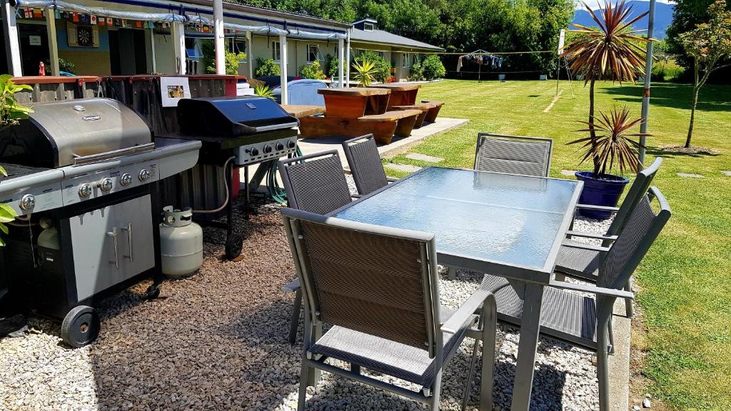 a table and chairs with a grill and a table and chairs at Happy Apple Backpackers in Motueka