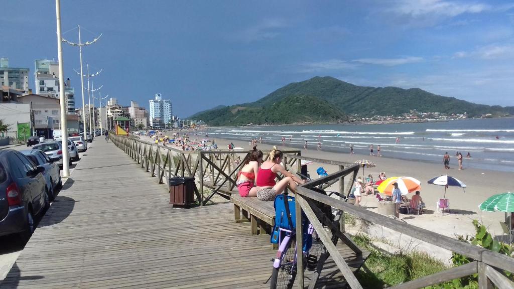 Due donne sedute su una panchina in spiaggia di Pousada Cama & Café a Navegantes