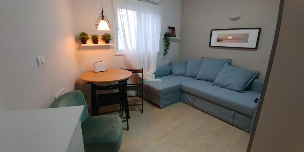 a living room with a blue couch and a table at Ramat Poleg, walk to beach in Netanya