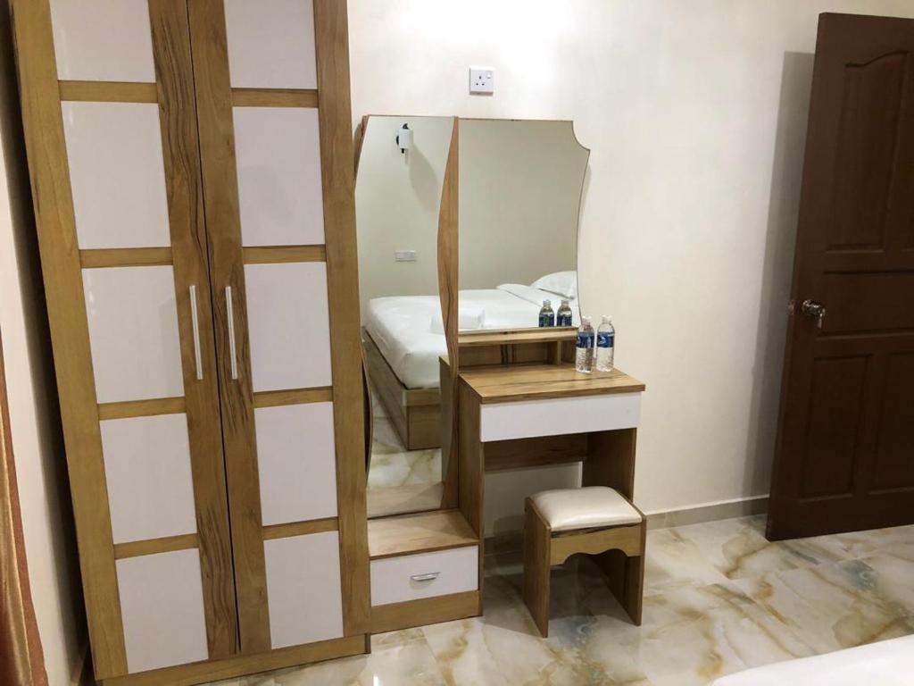 een spiegel in een kamer met een bed en een kruk bij CLASSIC KINABALU VILLA in Kota Kinabalu