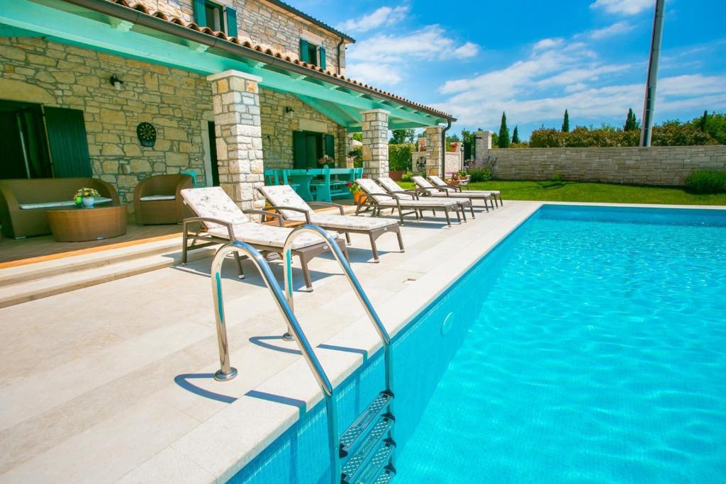 a swimming pool with chairs next to a house at Charming Villa Luce Ribari in Istria Countryside in Radetići