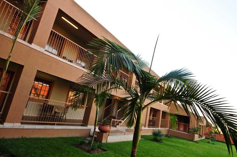 a building with a palm tree in front of it at Batter Boys Guest House in Pretoria