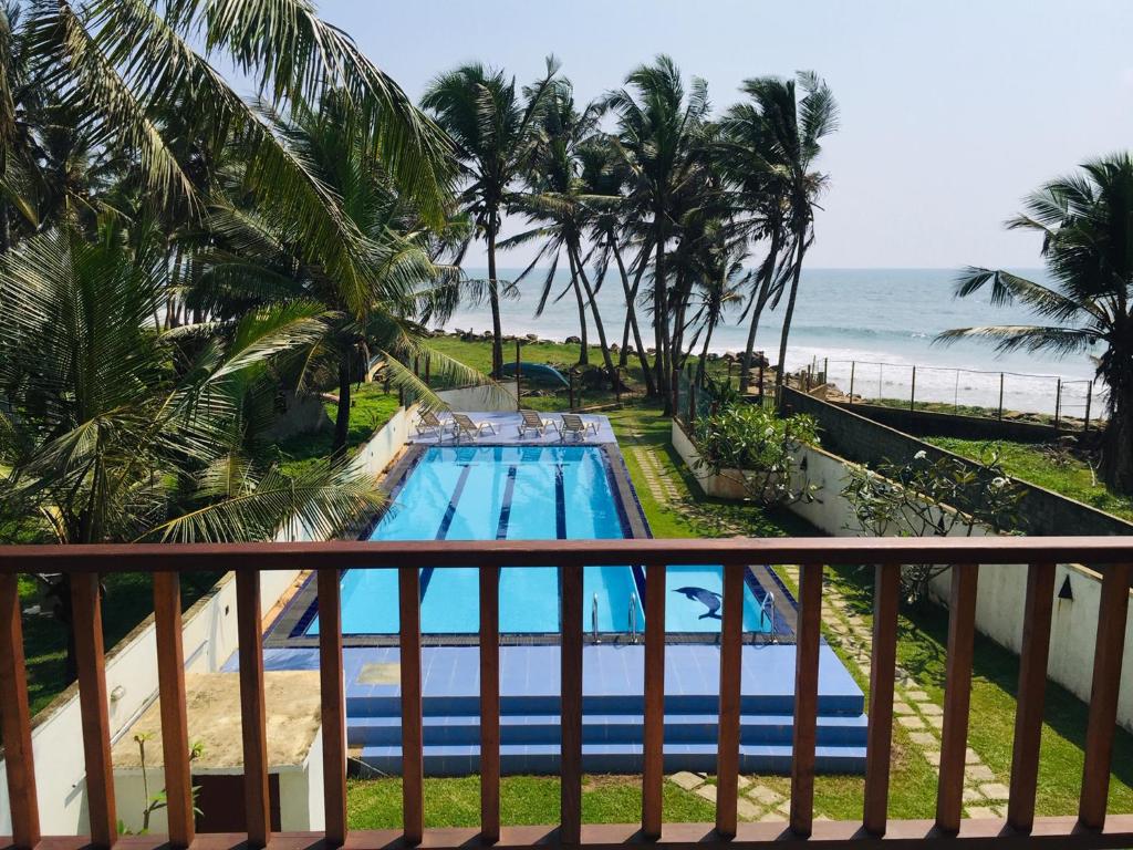 uma vista para a piscina a partir da varanda de um resort em Villa Ocean Dew - Beach Front em Galle