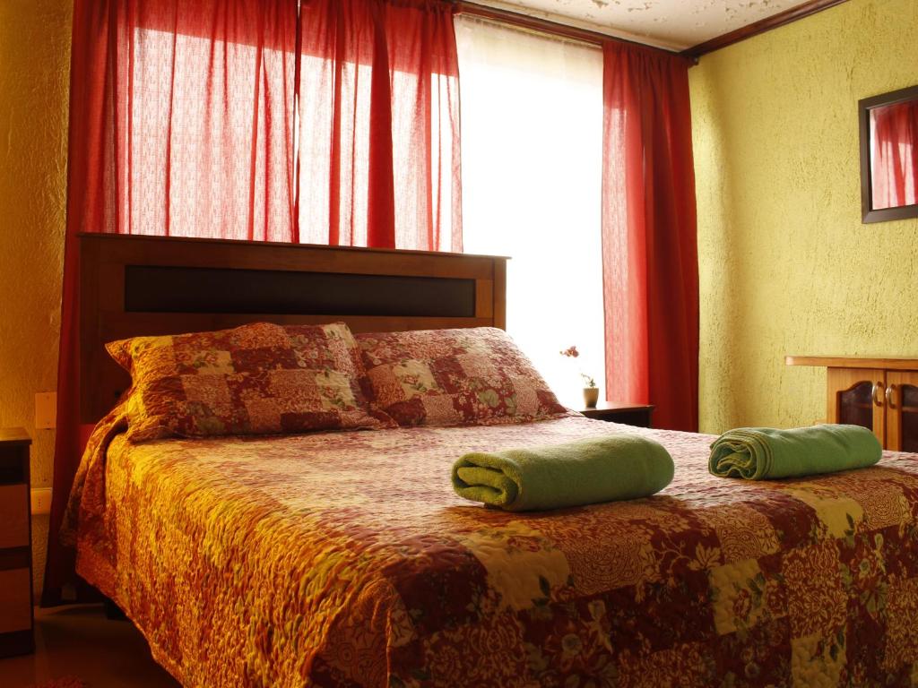 a bedroom with a bed with two green pillows on it at Hostal Inthalassa Caldera in Caldera