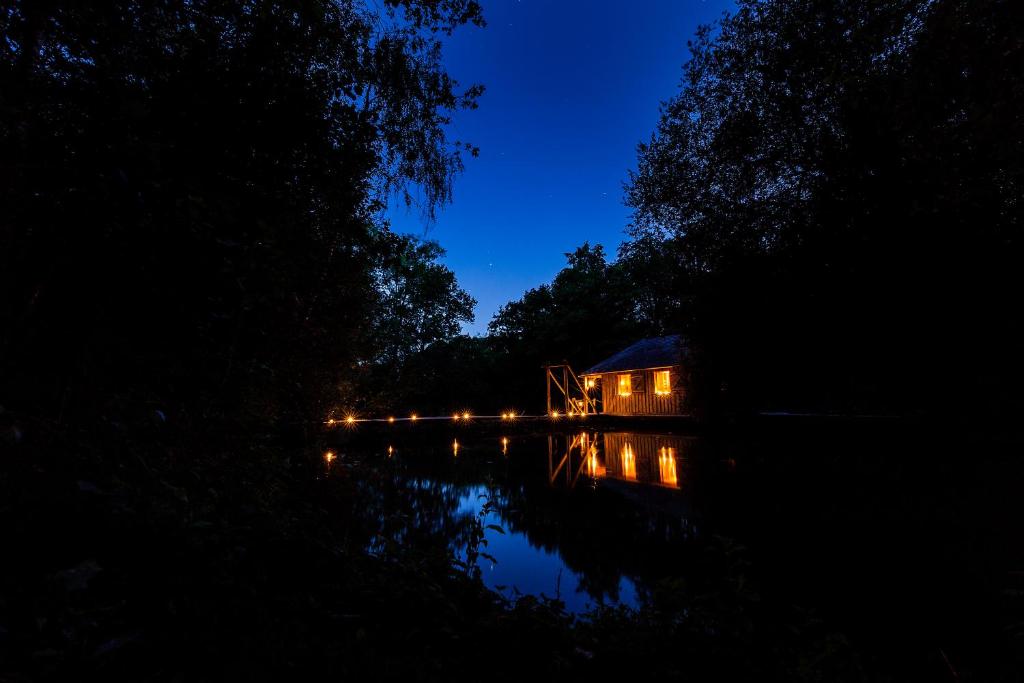 a house in the middle of a lake at night at Les Ecolodges de l&#39;Orbière in Forcé