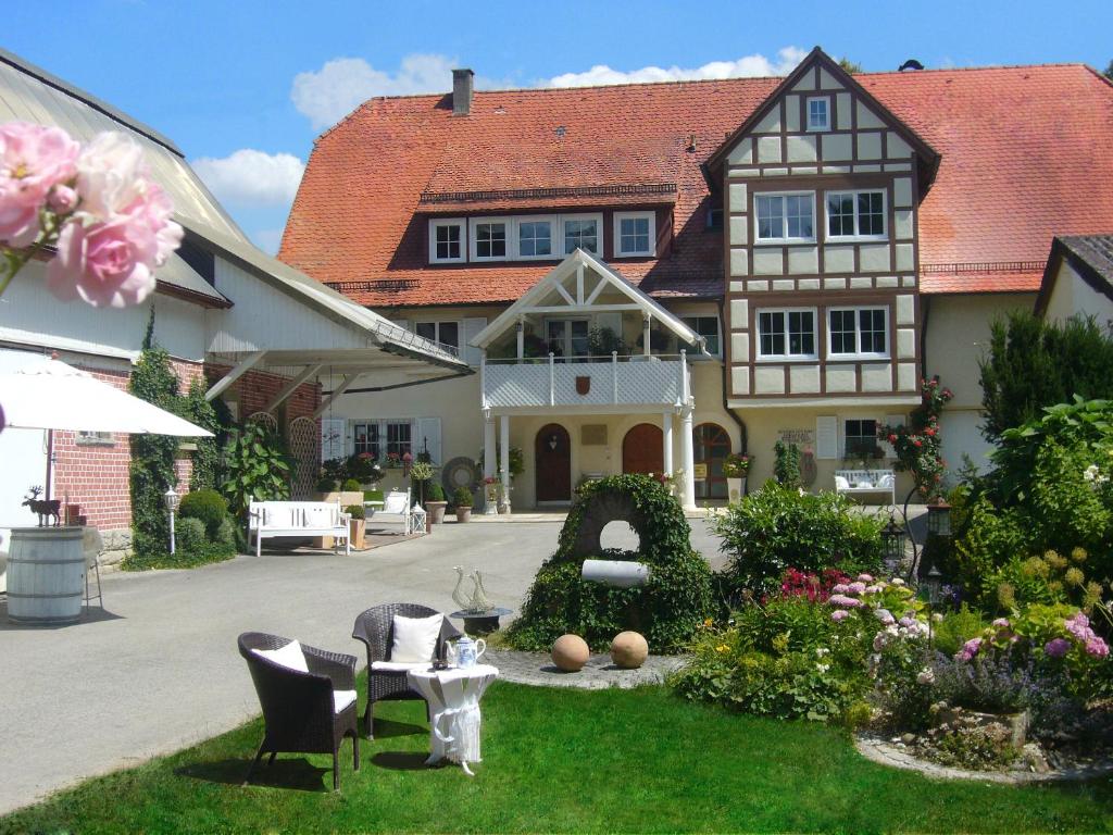 una casa con un patio con sillas y flores en Ferienidyll Aumühle "Muswiese" en Rot am See