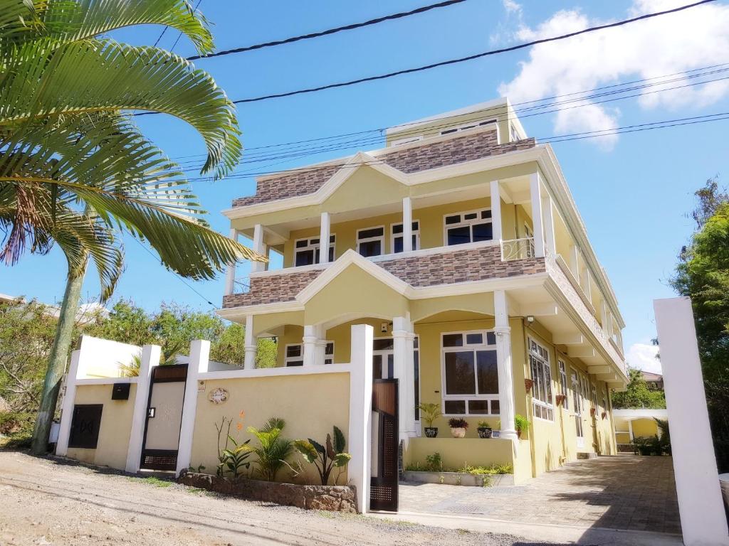 a white house with a palm tree in front of it at Colosseo Apartments in Grand Baie