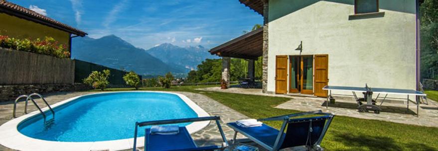 a swimming pool with two chairs and a house at Villa Betulla con piscina privata sul lago di Como in Colico