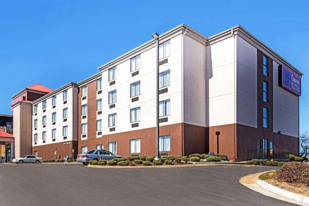 an apartment building with a car parked in a parking lot at Comfort Suites Tuscaloosa near University in Tuscaloosa