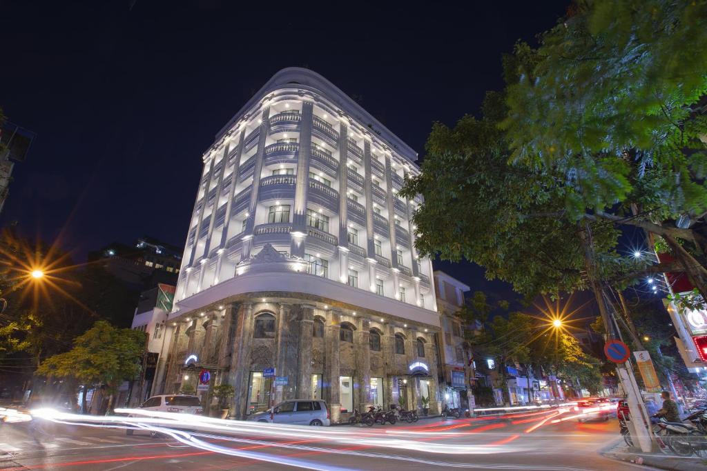 een groot gebouw in een stadsstraat 's nachts bij Halais Hotel in Hanoi