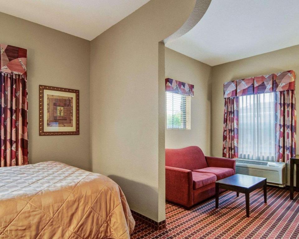 een slaapkamer met een bed, een bank en ramen bij Affordable Suites of America Rogers - Bentonville in Rogers