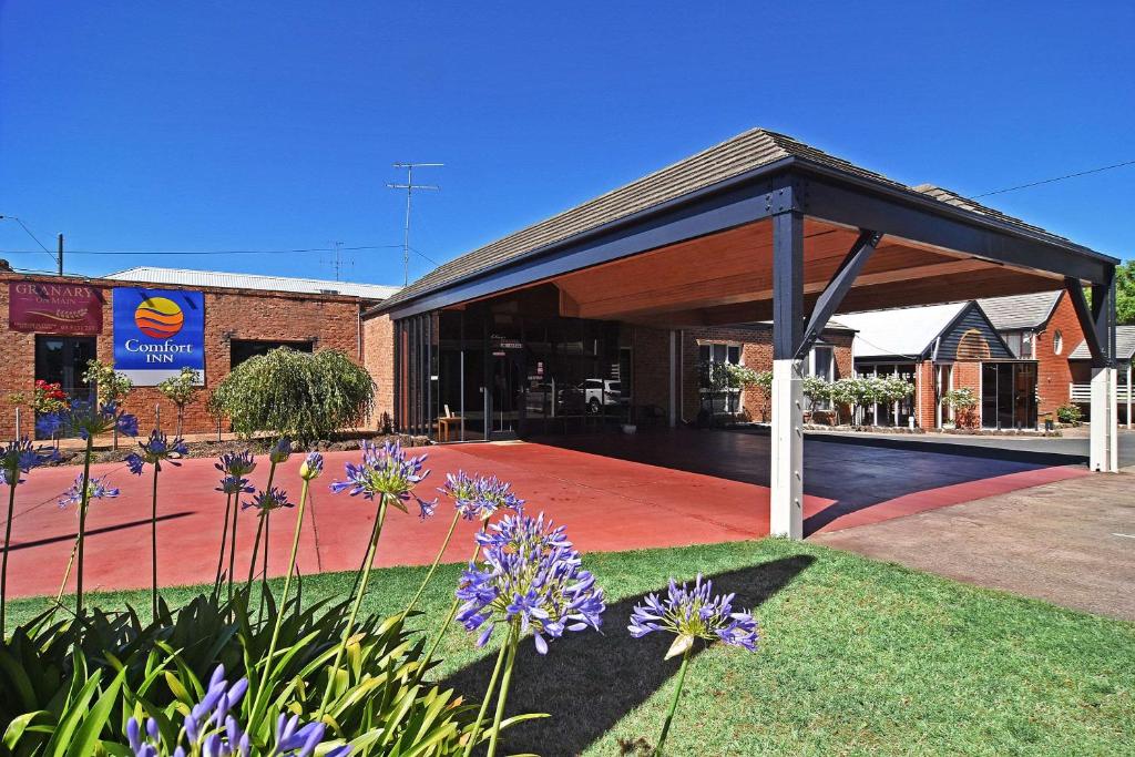 a pavilion in front of a building with purple flowers at Main Lead Ballarat Motel in Ballarat