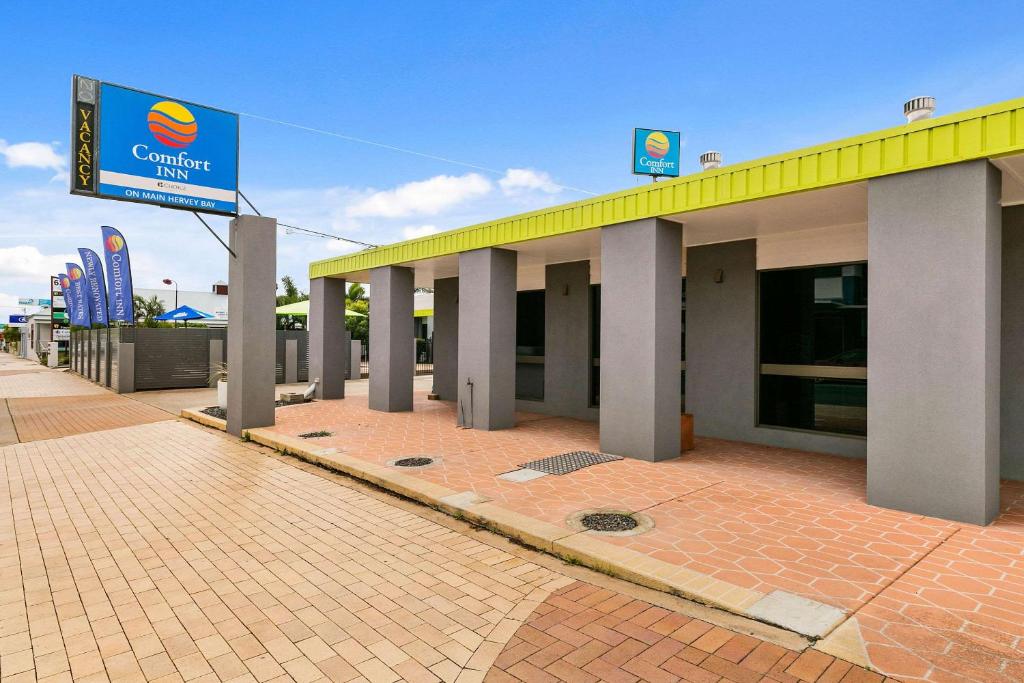 un edificio con una señal delante de él en Comfort Inn on Main Hervey Bay, en Hervey Bay