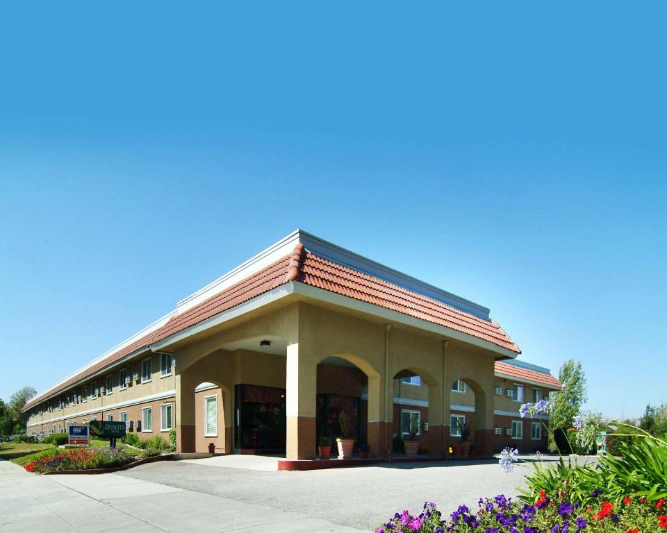 a large building with flowers in front of it at Quality Inn Santa Clara Convention Center in Sunnyvale