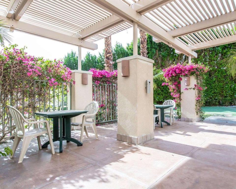 un patio con mesas y sillas bajo una pérgola en Comfort Suites Palm Desert I-10, en Palm Desert