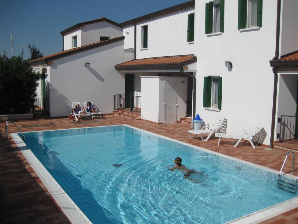 Ein Mann, der in einem Pool neben einem Gebäude schwimmt. in der Unterkunft Residence Tamerici in Caorle