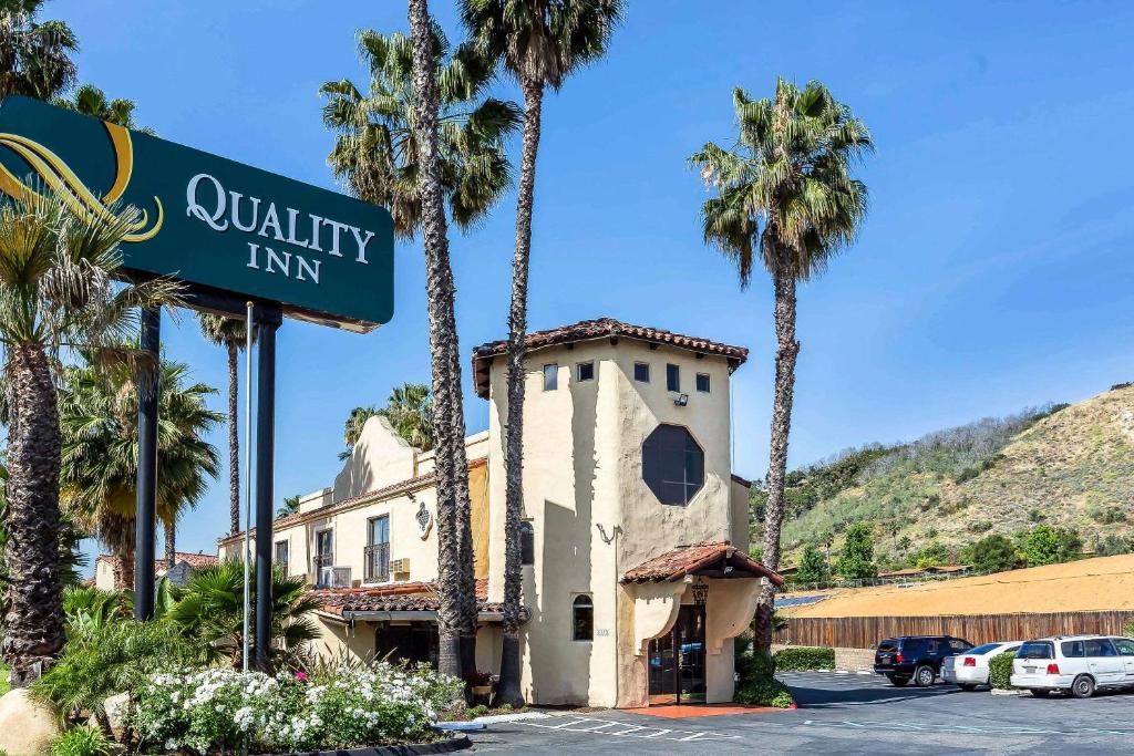 a street sign in front of a building with palm trees at Quality Inn Fallbrook in Fallbrook