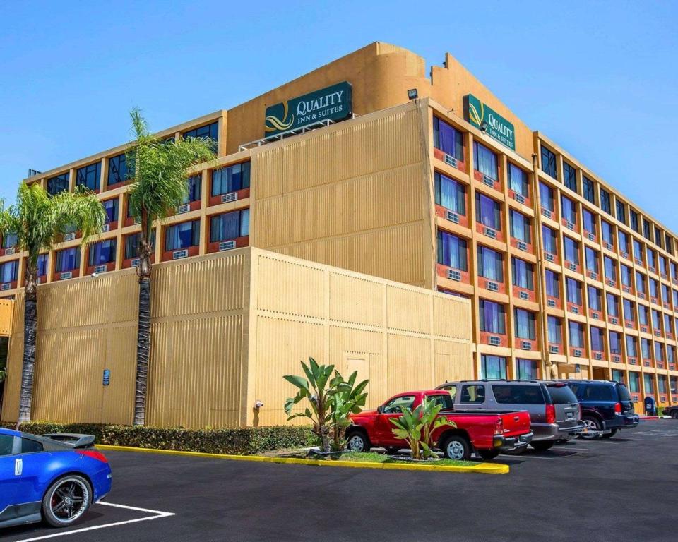 Quality Inn & Suites Montebello - Los Angeles في مونتيبيلو: مبنى الفندق مع وجود سيارات تقف في موقف للسيارات