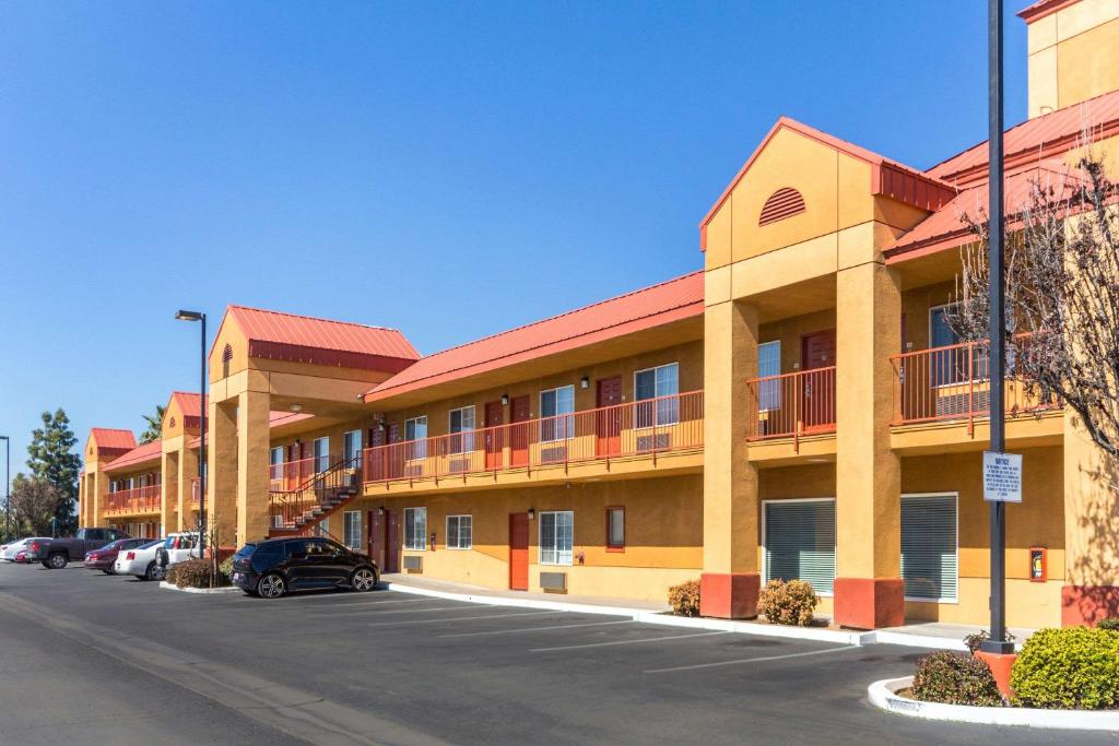 a building with cars parked in a parking lot at Quality Inn Fresno Near University in Fresno