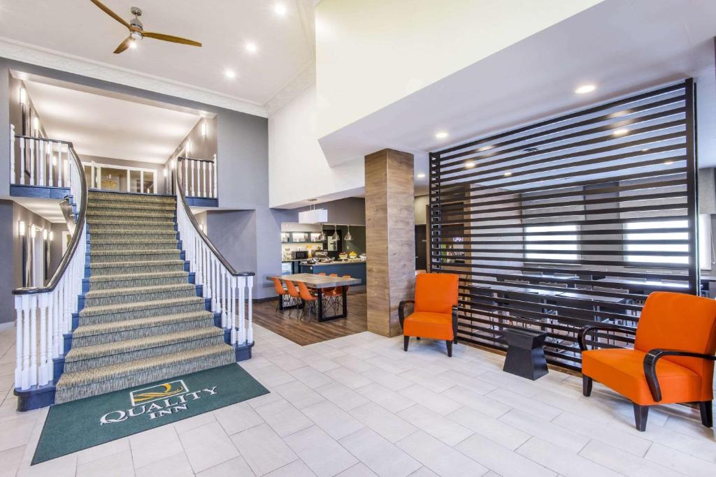 a lobby with a staircase and orange chairs at Quality Inn Airport West in Mississauga
