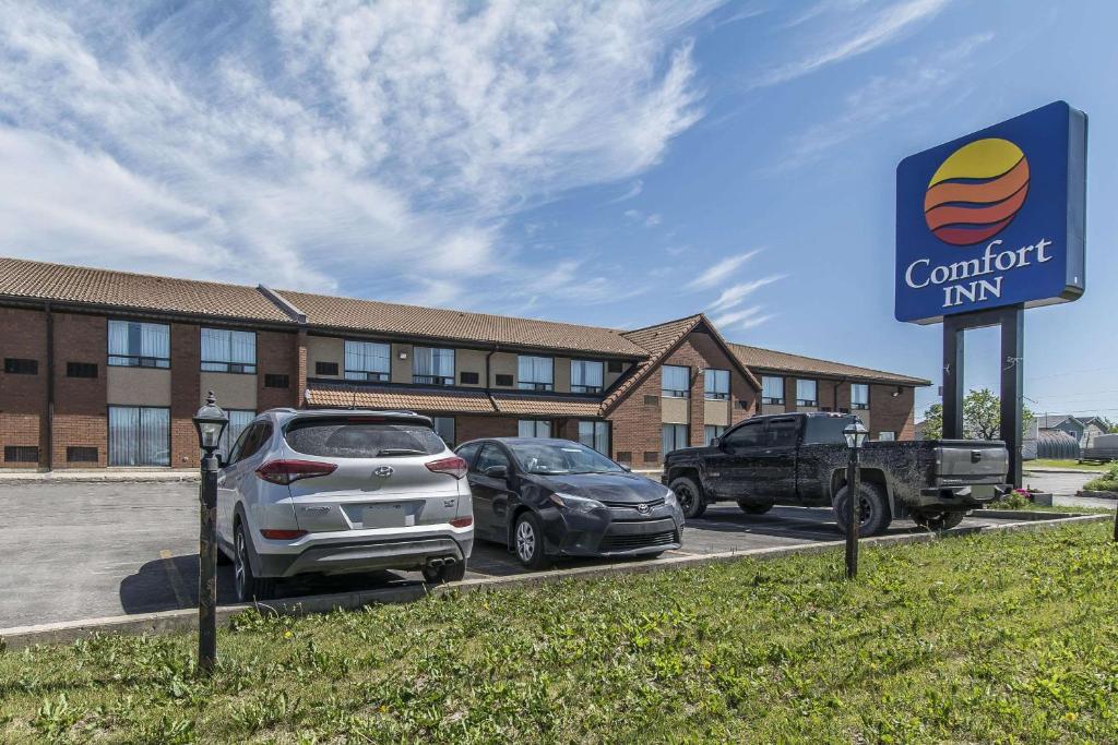 um stand de automóveis com carros estacionados em frente a um edifício em Comfort Inn Kapuskasing em Kapuskasing