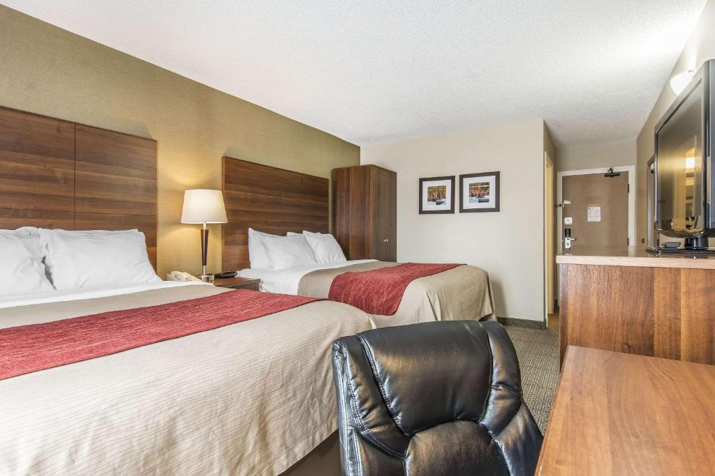a hotel room with two beds and a chair at Comfort Inn in Huntsville