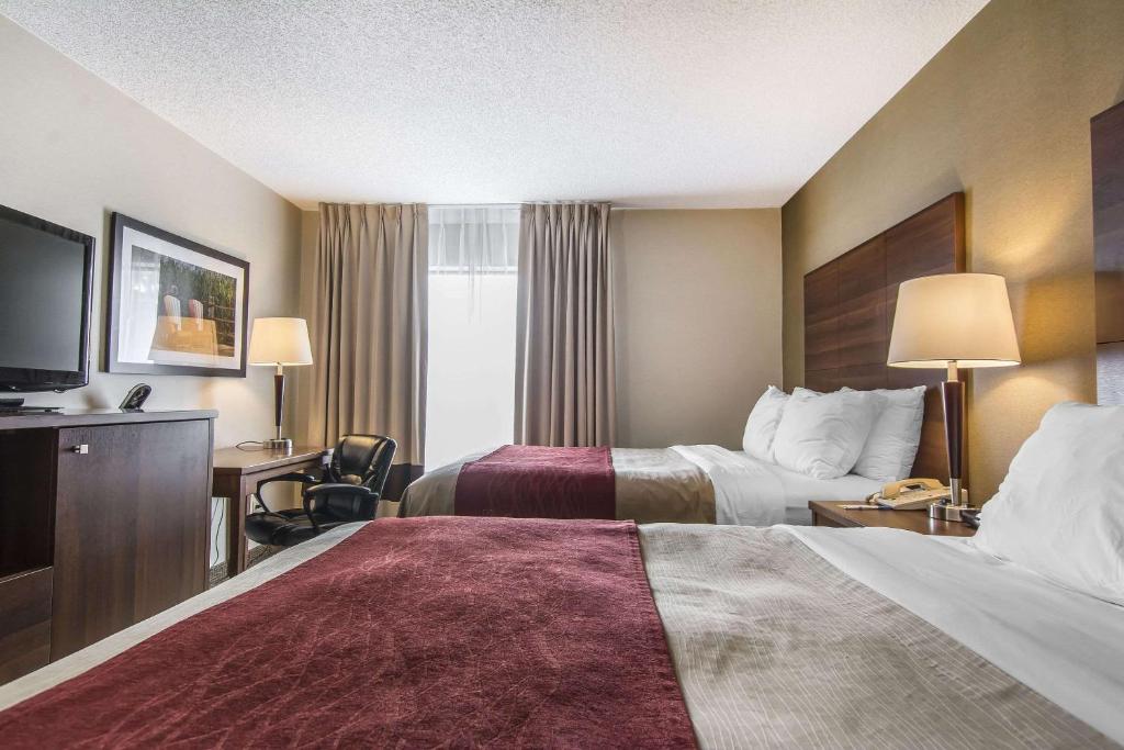 a hotel room with two beds and a television at Comfort Inn in Huntsville