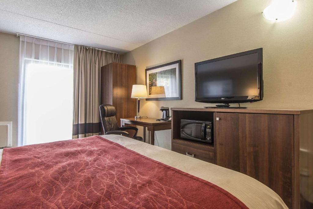 a hotel room with a bed and a flat screen tv at Comfort Inn in Huntsville