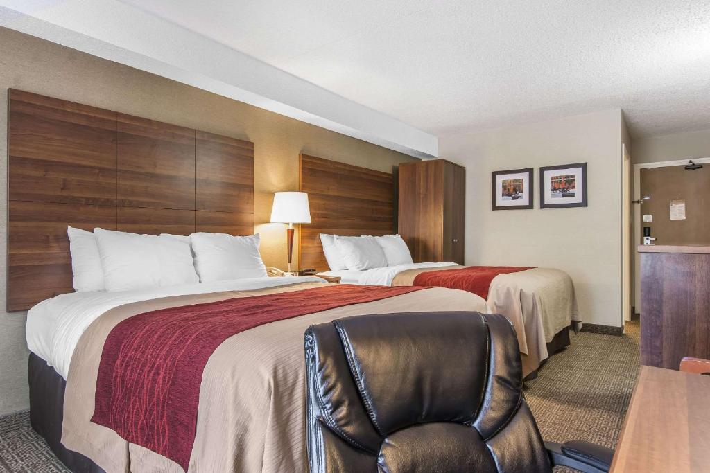 a hotel room with two beds and a chair at Comfort Inn in Huntsville