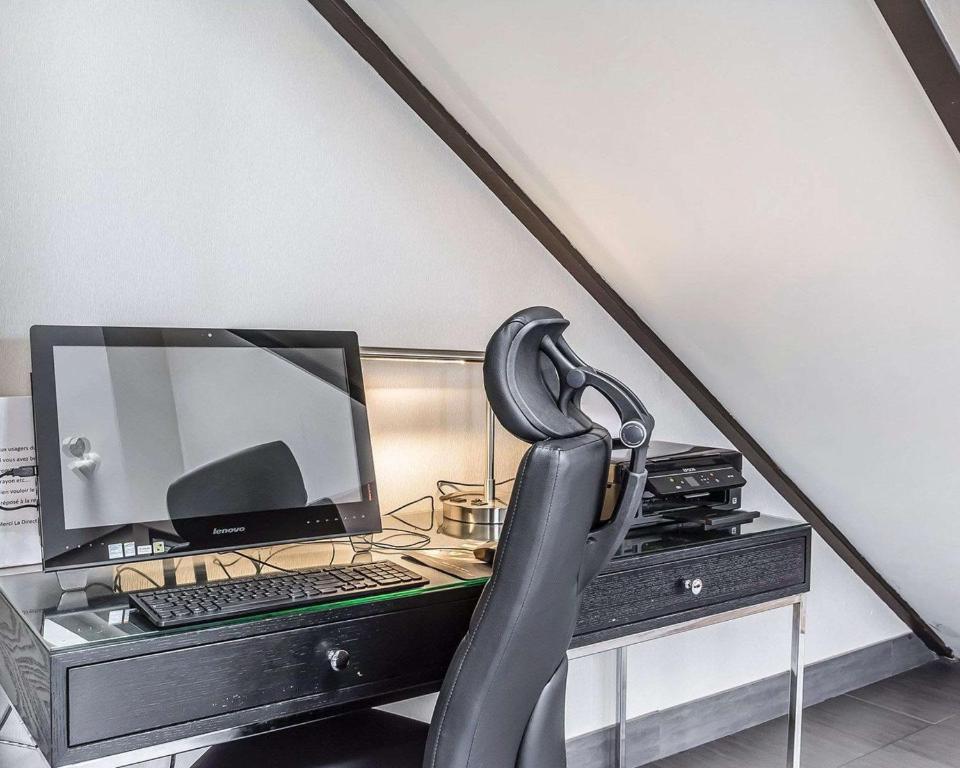a chair in front of a desk with a computer at Comfort Inn in Saguenay