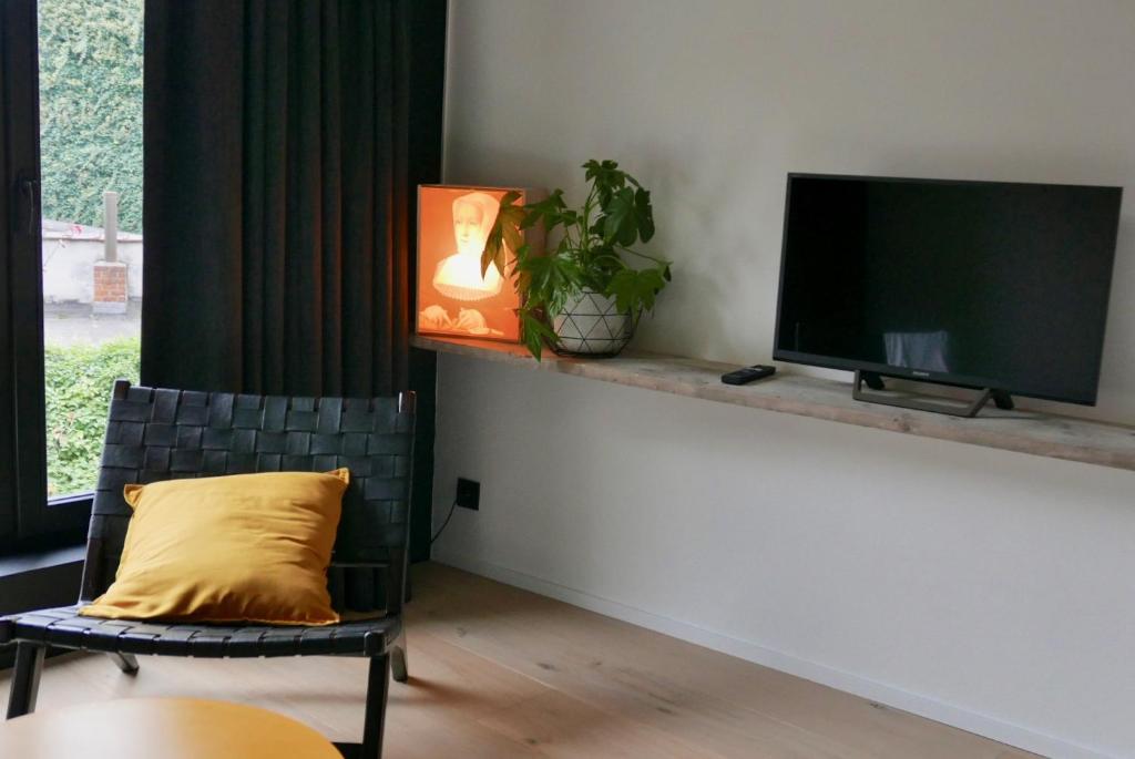a living room with a tv and a chair with a yellow pillow at Margaretha's Room in Mechelen