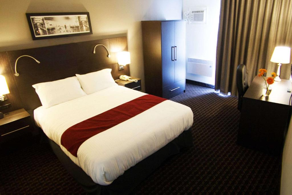 um quarto de hotel com uma cama grande num quarto em Hôtel Le Principal em Granby