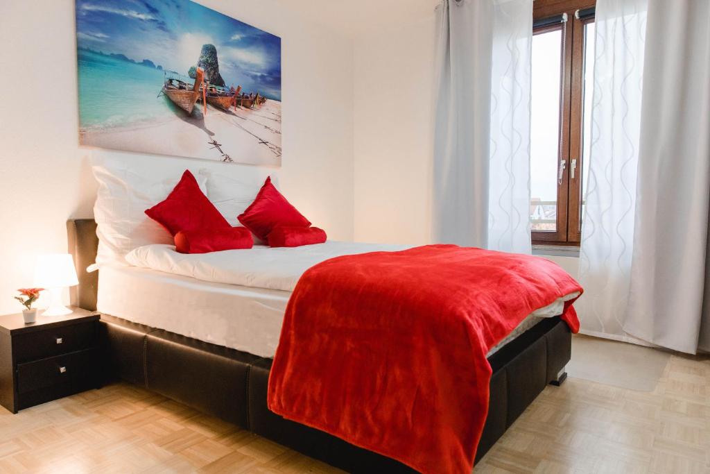 ein Schlafzimmer mit einem Bett mit roten Kissen und einem Gemälde in der Unterkunft Luxury flat between Cologne and Bonn and Phantasialand Bruhl in Wesseling