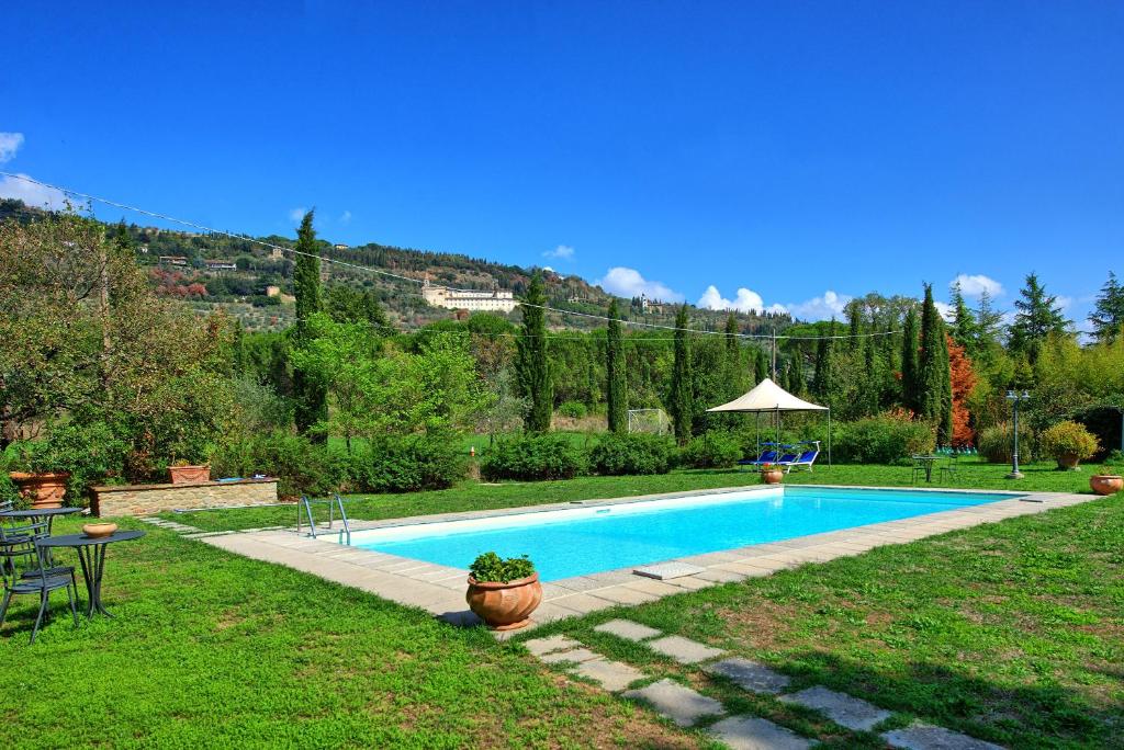 una piscina in un cortile con tavolo e sedie di Villa Elisa by PosarelliVillas a Cortona