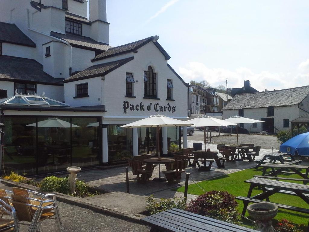 ein Restaurant mit Tischen und Sonnenschirmen vor einem Gebäude in der Unterkunft The Pack o' Cards in Combe Martin