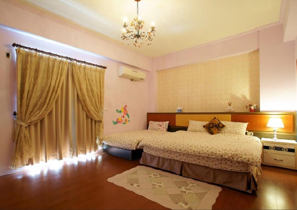 a bedroom with two beds and a chandelier at Garden Rose Homestay in Taitung City