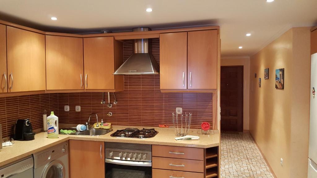 La cuisine est équipée de placards en bois et d'un four avec plaques de cuisson. dans l'établissement Apartamento Altura II, à Altura