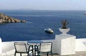 a table and two chairs and a boat in the water at Ios Pelagos in Ios Chora