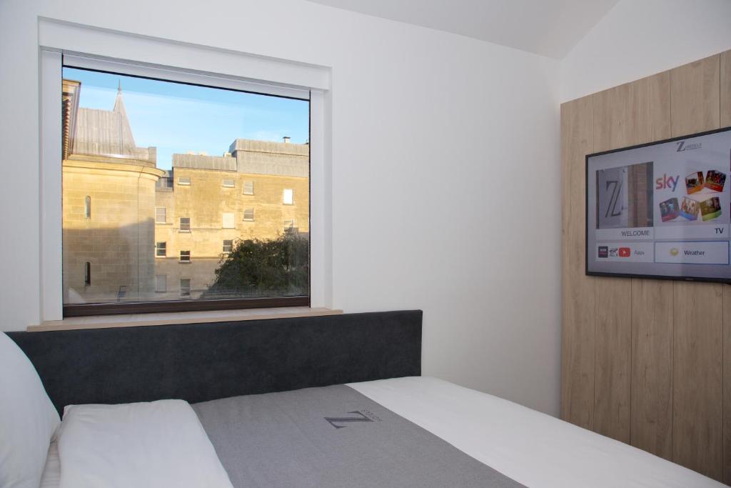 a bedroom with a bed and a window with a building at The Z Hotel Bath in Bath