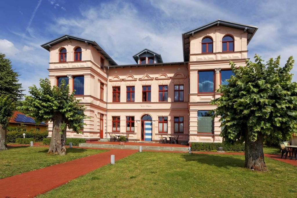 uma casa grande com duas árvores em frente em Villa Maria Wohnung 10 em Ostseebad Koserow