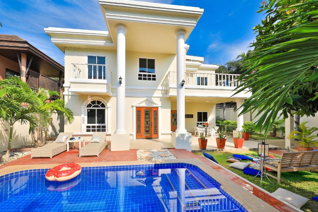 a villa with a swimming pool in front of a house at Sweet Villas Pattaya in Pattaya South