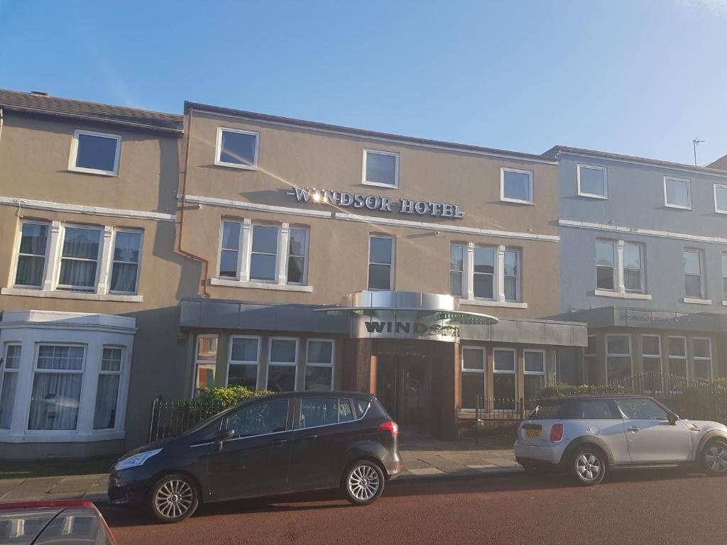 dois carros estacionados em frente a um hotel em The Windsor Hotel em Whitley Bay