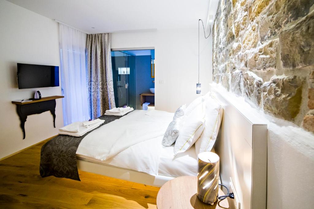 a hotel room with a bed and a stone wall at MEMENTO B&B Piran in Piran
