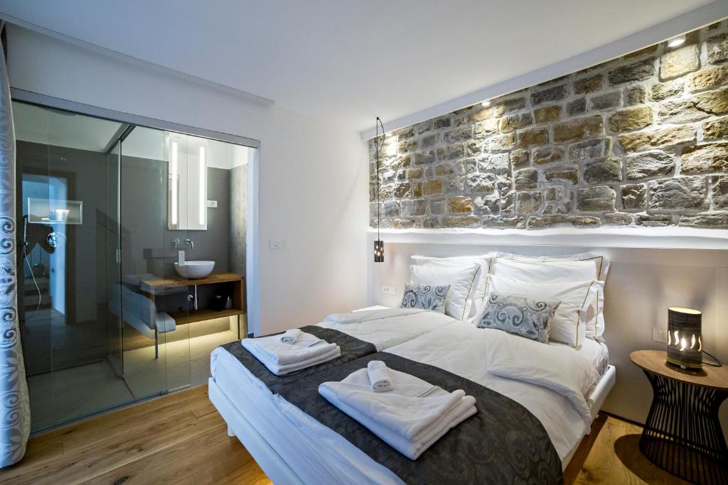a bedroom with a large bed and a stone wall at MEMENTO B&B Piran in Piran