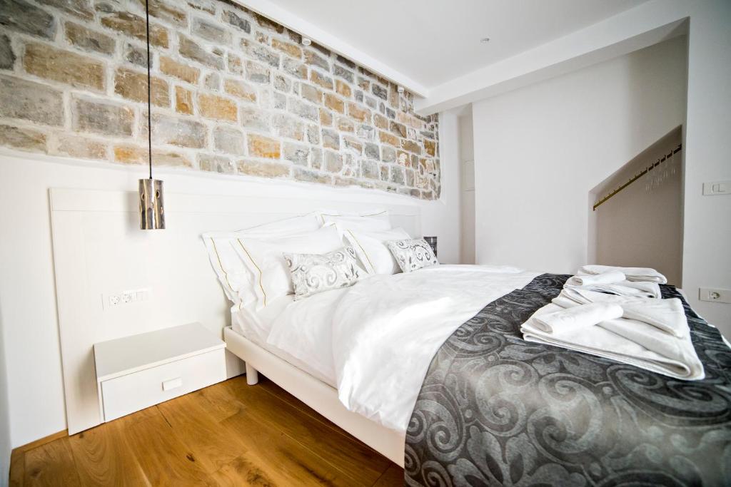 a bedroom with a large bed with a brick wall at MEMENTO B&B Piran in Piran