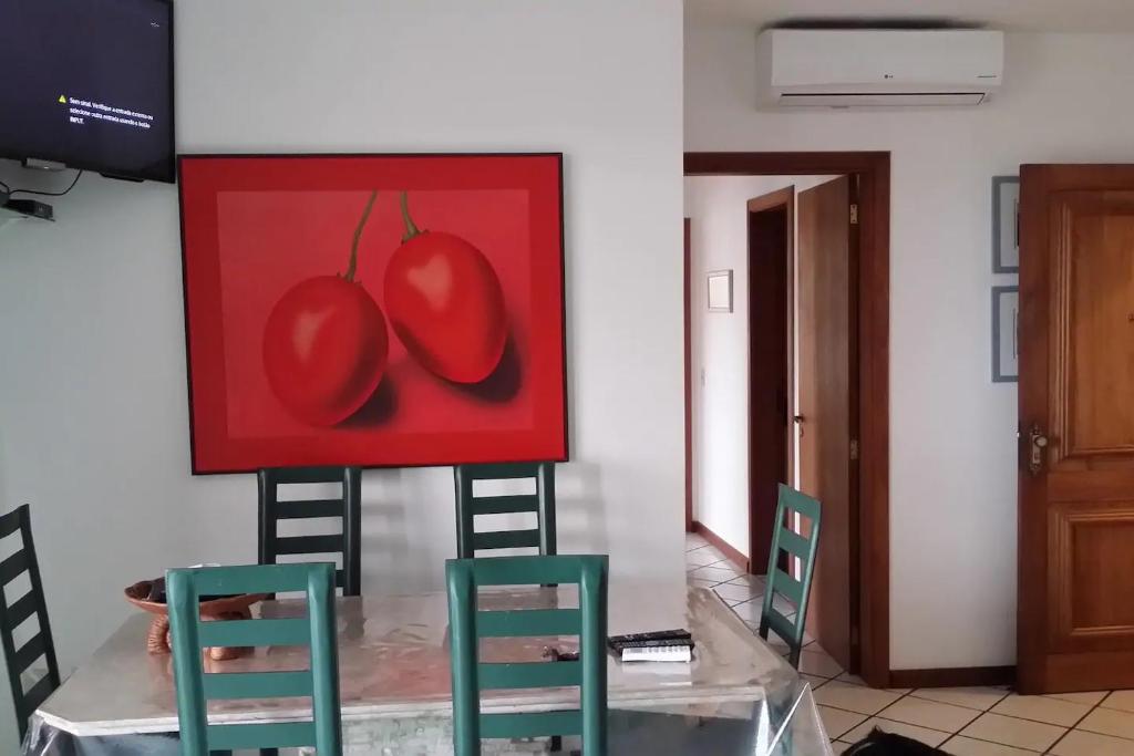 una pintura de dos tomates y dos sillas en una habitación en APTO c VISTA MARAVILHOSA DO MAR, PERTO DA PRAIA, en Torres