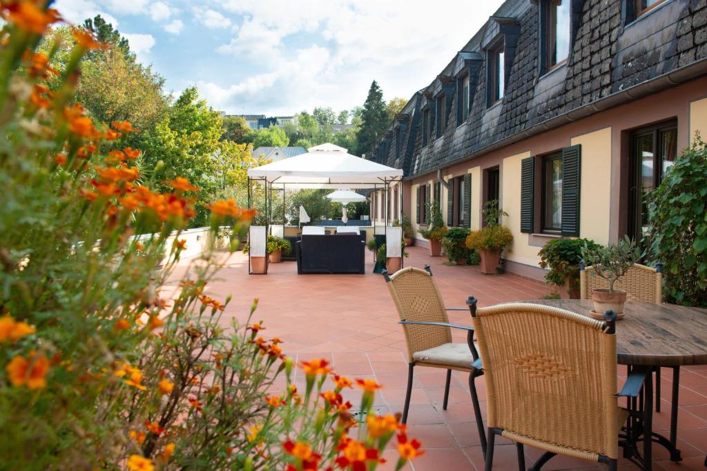 eine Terrasse mit Stühlen, einem Tisch und einem Sonnenschirm in der Unterkunft Blesius Garten in Trier