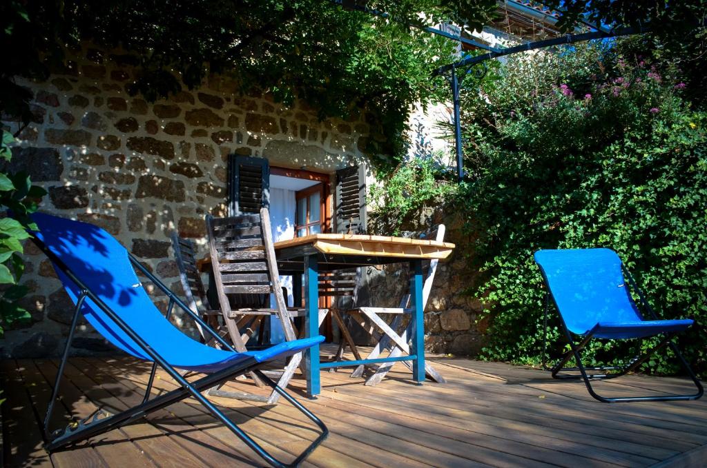 twee blauwe stoelen en een tafel op een terras bij Le Petit Rias Gîte Soleil in Saint Maurice en Chalencon