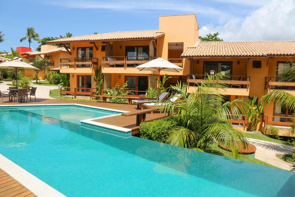 a villa with a swimming pool in front of a house at Cores do Arraial Residence Hotel in Arraial d'Ajuda